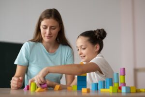 Therapist guiding a child through a structured play activity using colorful blocks as part of modern autism therapy focused on learning, communication, and skill development.